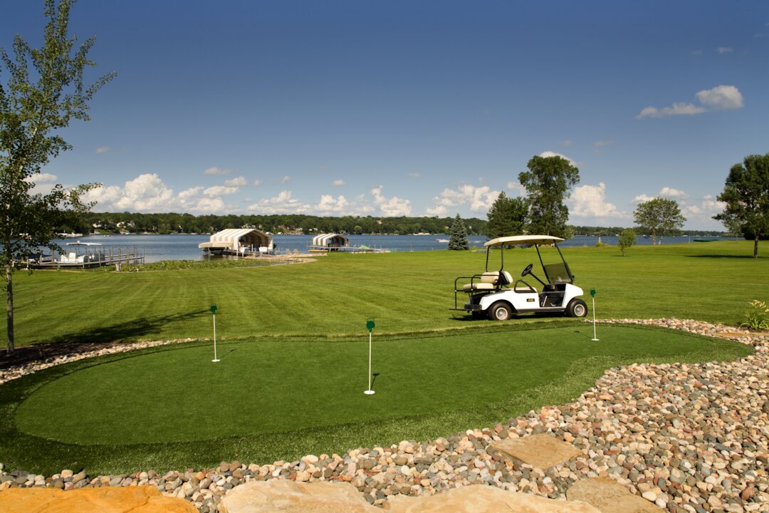 Golf cart on lakeside putting green landscape.