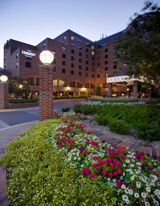 Hotel exterior with flower garden at dusk.