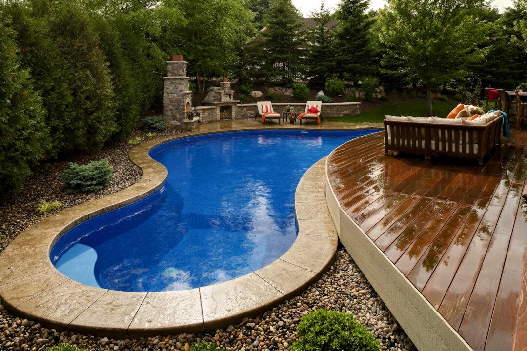 Backyard with pool, deck, and fireplace.