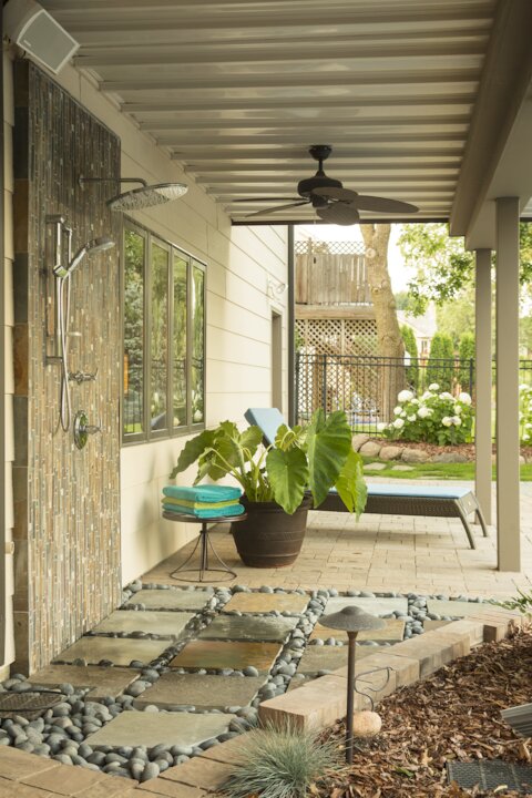 Modern patio with outdoor shower and seating area.