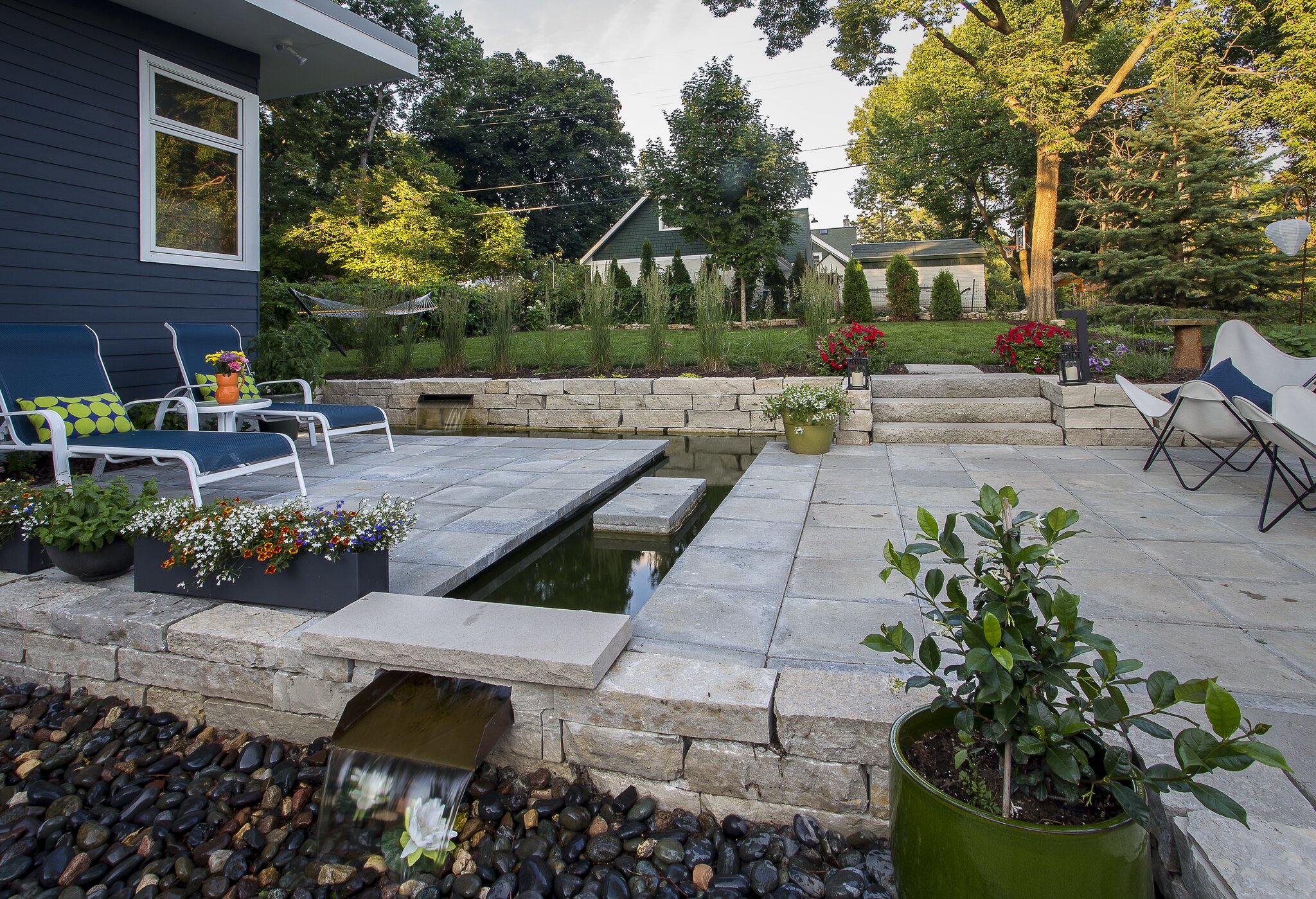 Modern patio with chairs and water feature.