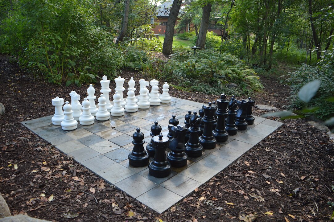 Outdoor chessboard with large black and white pieces.