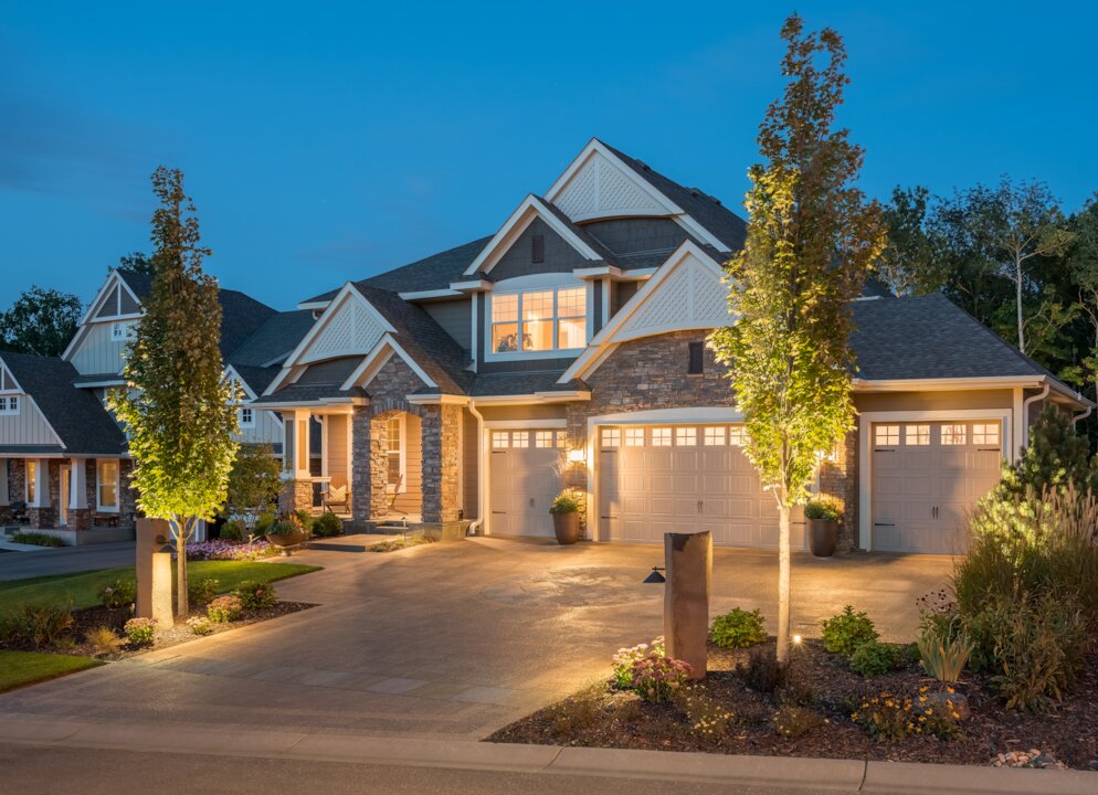 Modern suburban house at dusk with lit driveway.