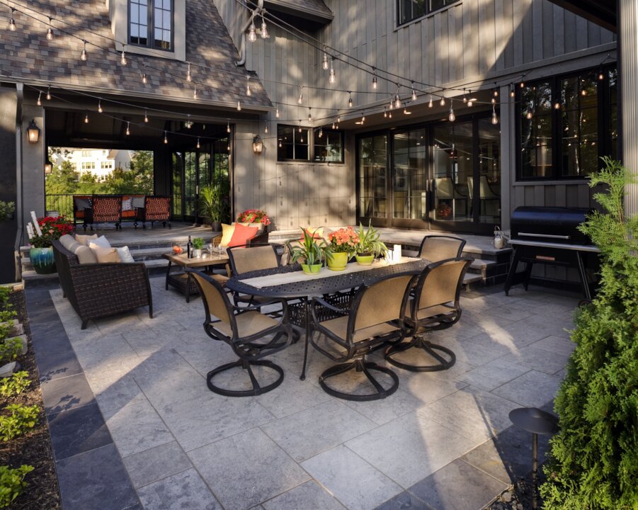 Modern patio with dining area and string lights.