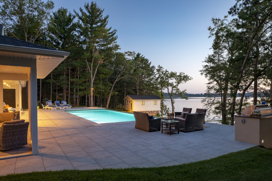 Modern lakeside patio with pool and seating area.