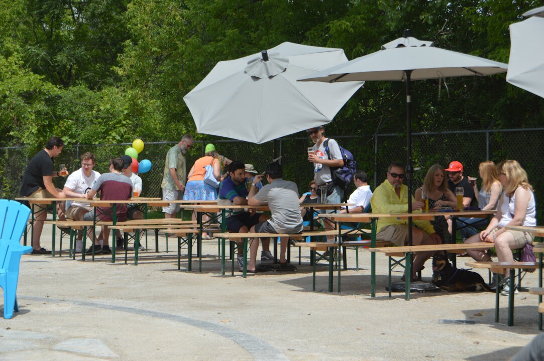 People socializing outdoors at a picnic table gathering.