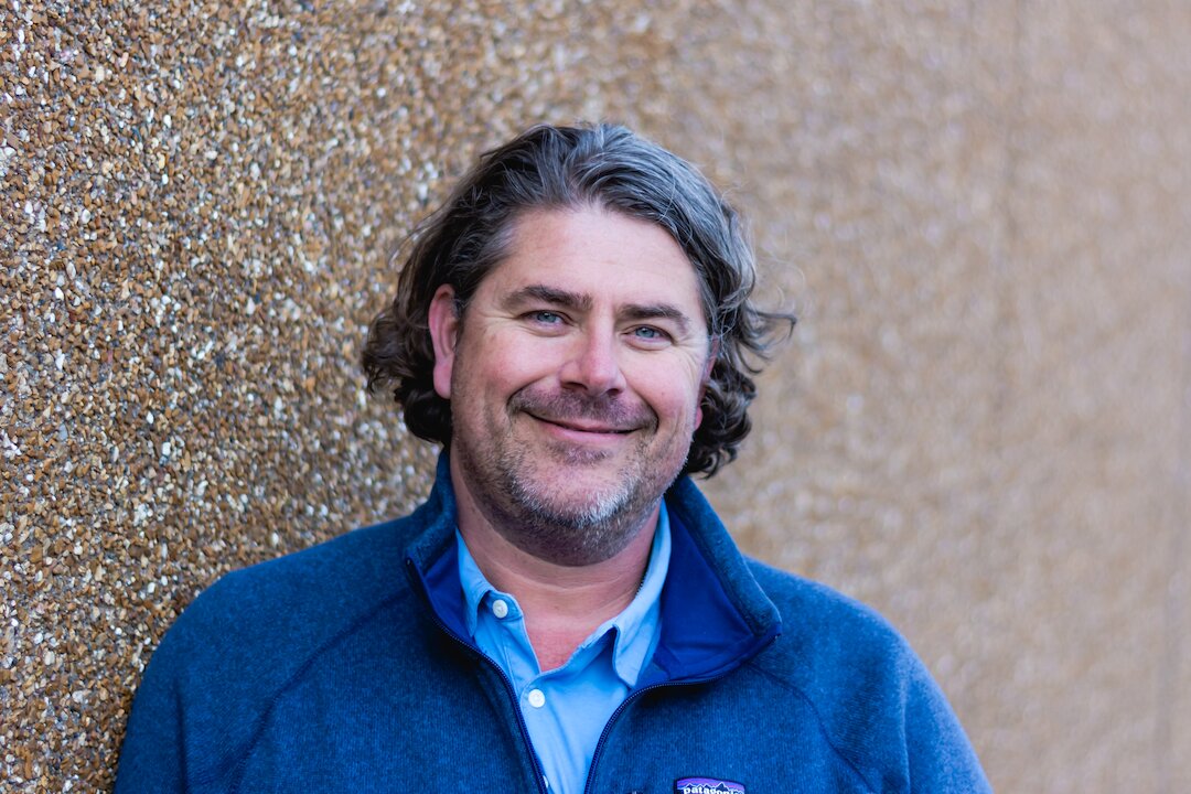 Smiling person in blue jacket outdoors