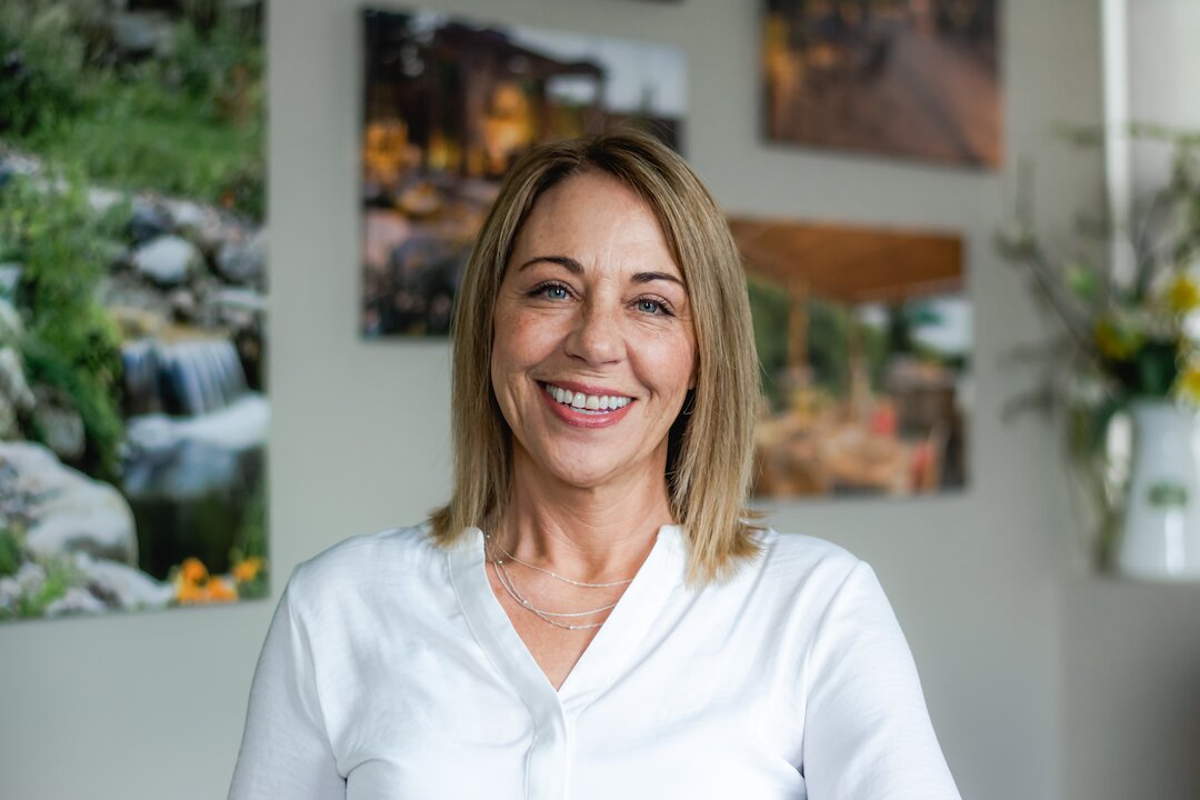 Smiling woman in white shirt indoors.