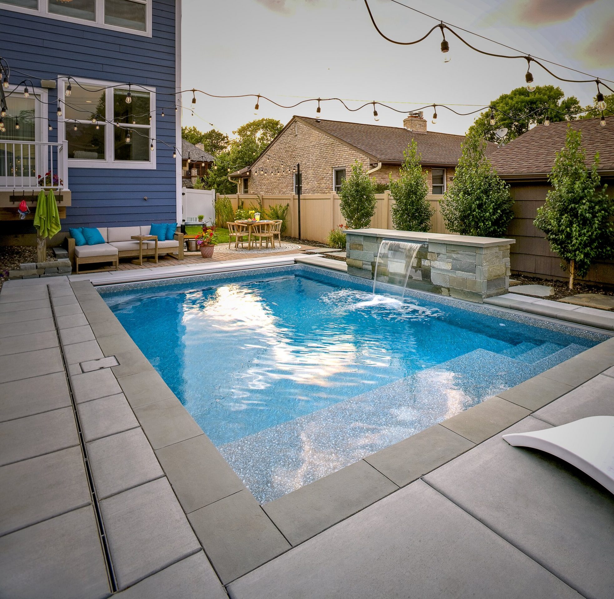 Modern backyard pool with water feature and seating.