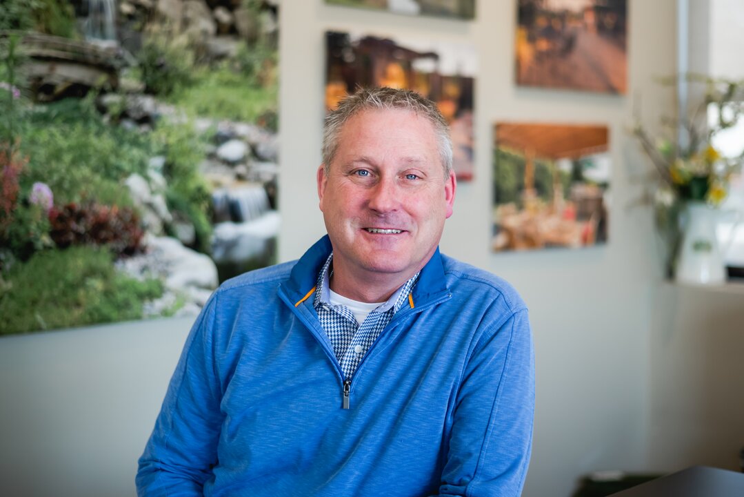 Smiling man in blue sweater indoors.