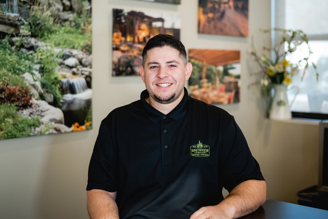Smiling man in a black polo shirt indoors.