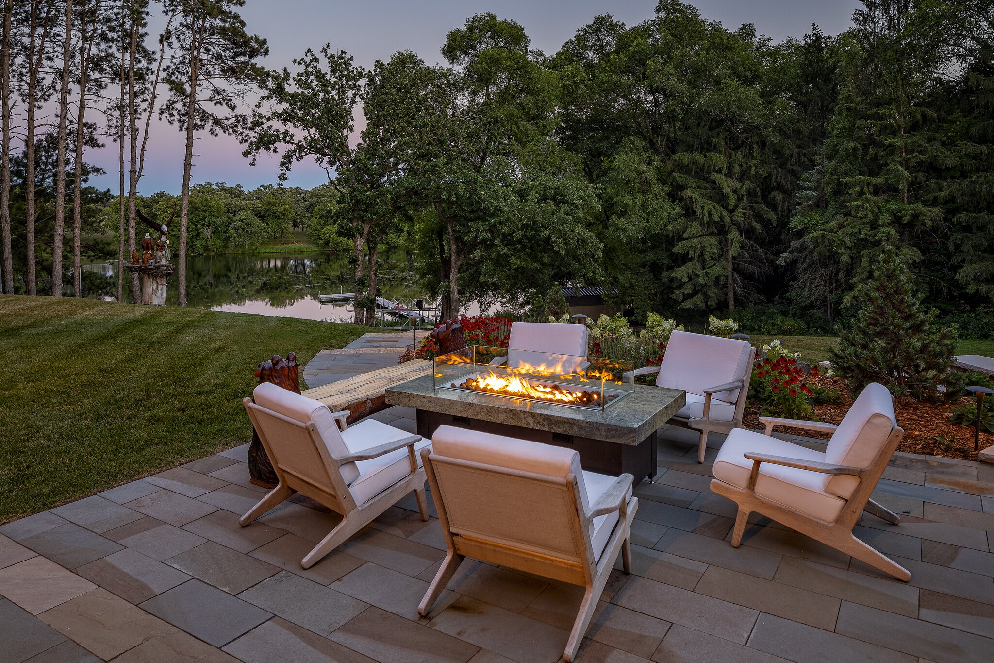 Patio with fire pit overlooking serene lake.