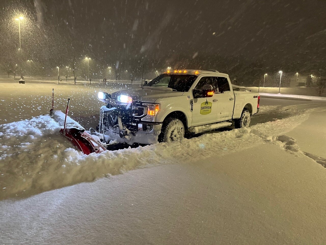 Snow plow truck clearing snow at night.