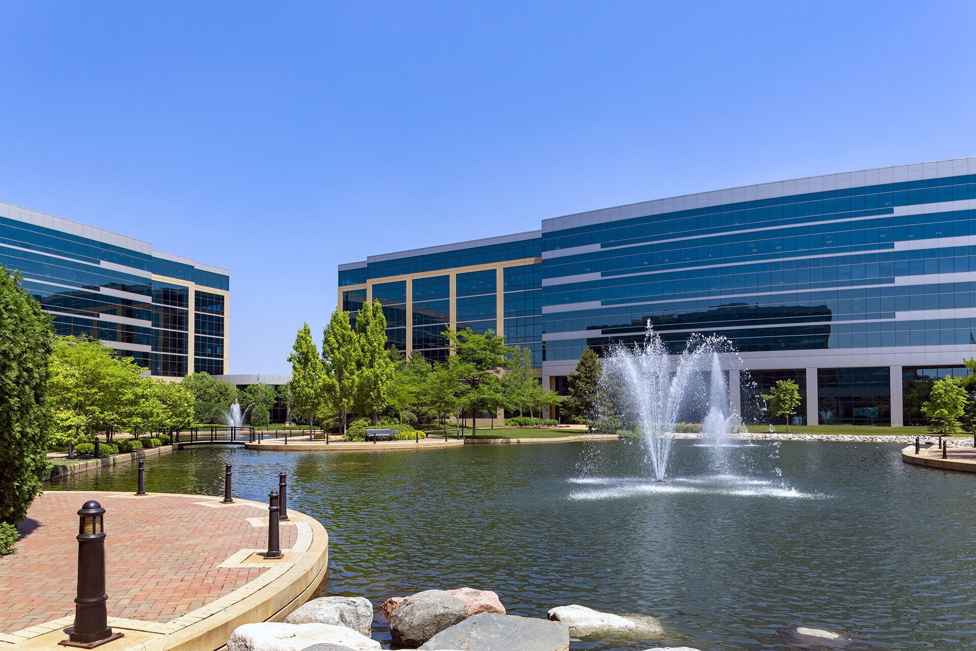 Modern office buildings with fountain and trees.