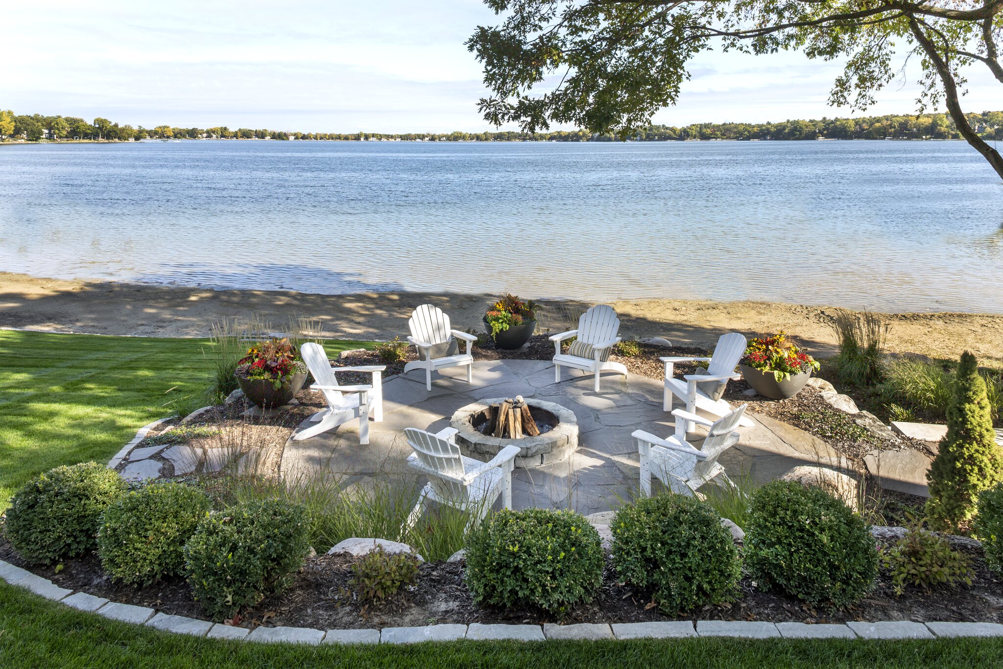 Lakeside patio with chairs and fire pit.