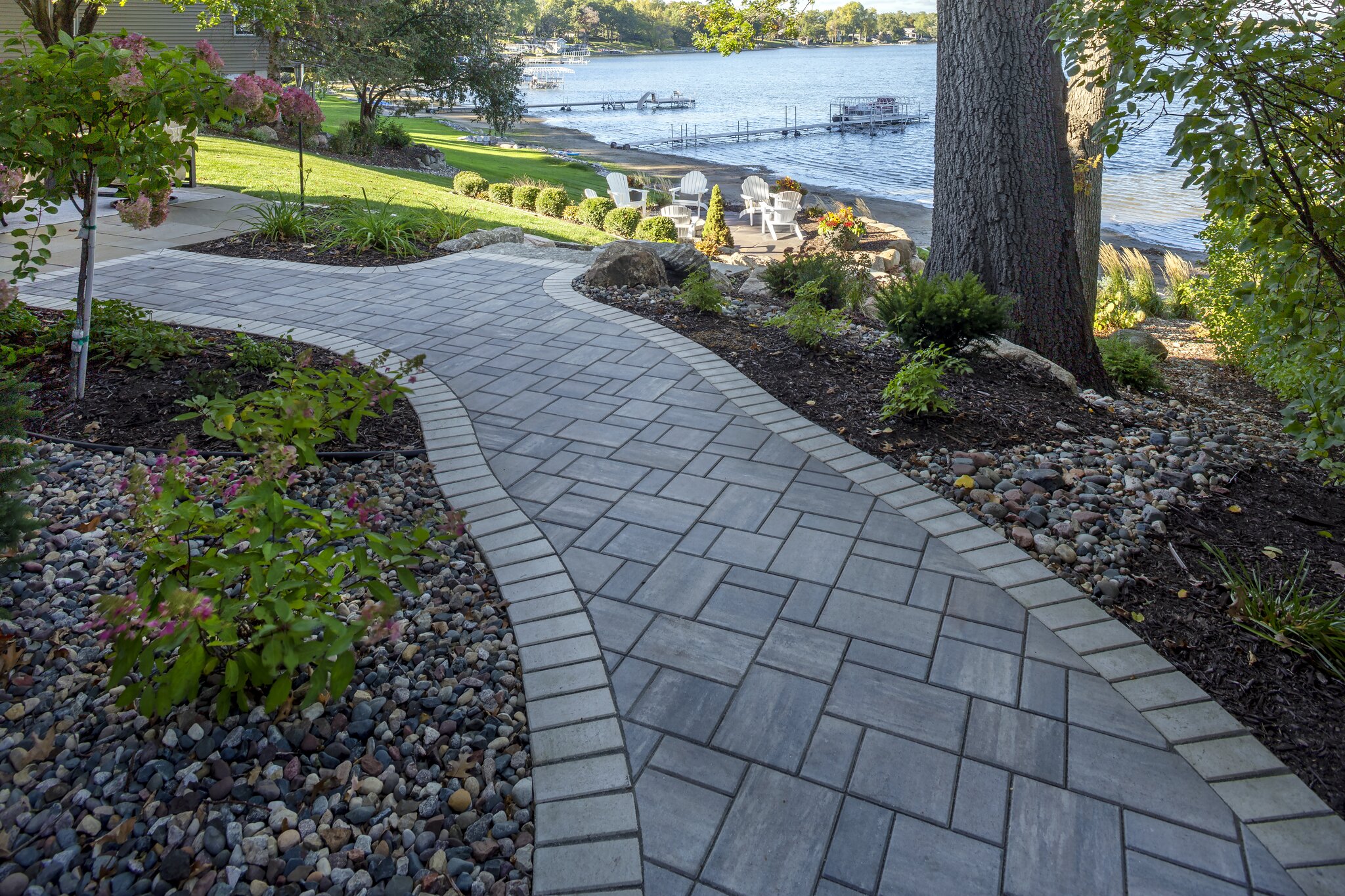 Paved garden walkway leading to lake view.