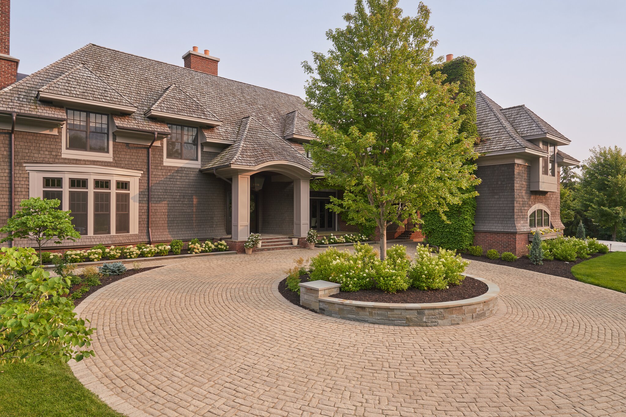 Luxurious brick house with landscaped circular driveway.