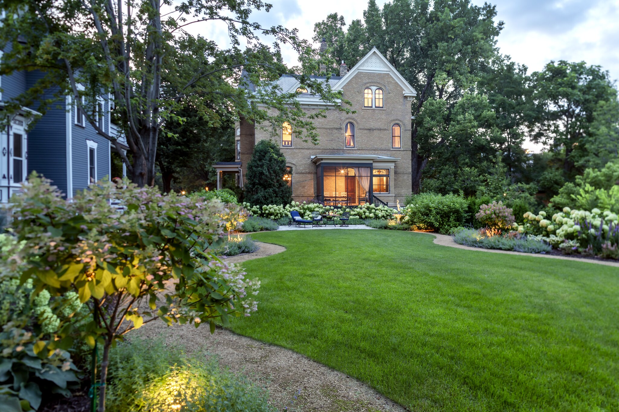 Elegant brick house with lush garden landscape.