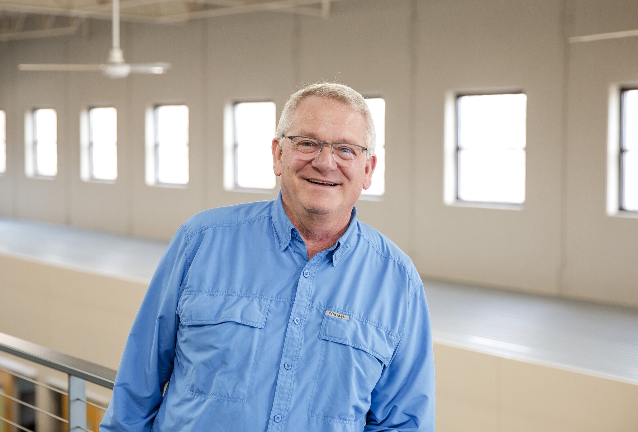 Man in blue shirt smiling indoors.