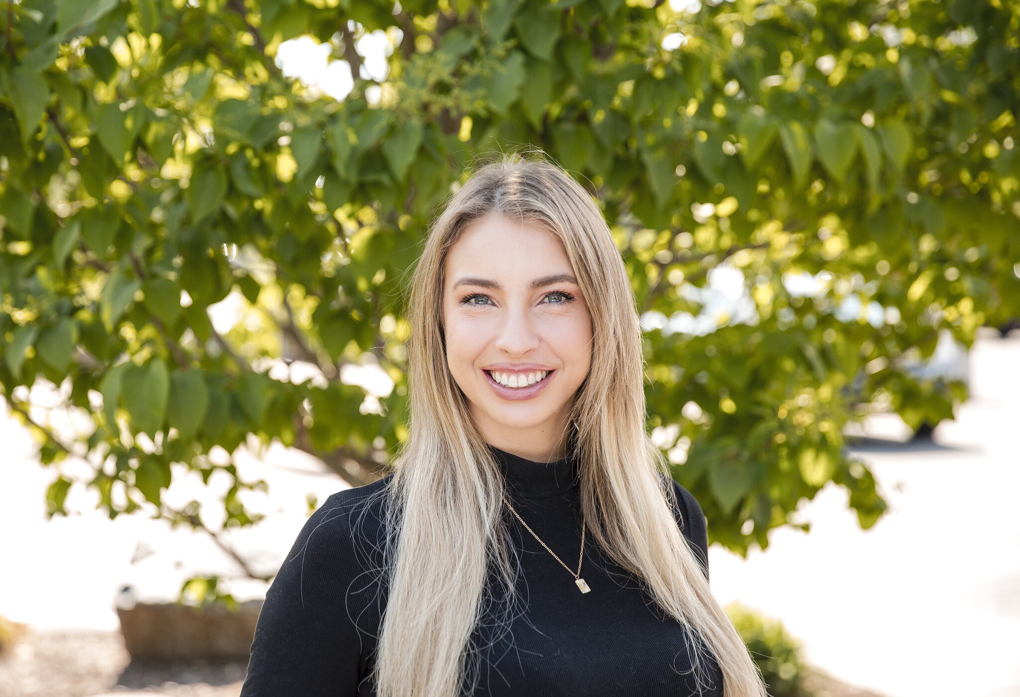 Smiling woman in front of green tree