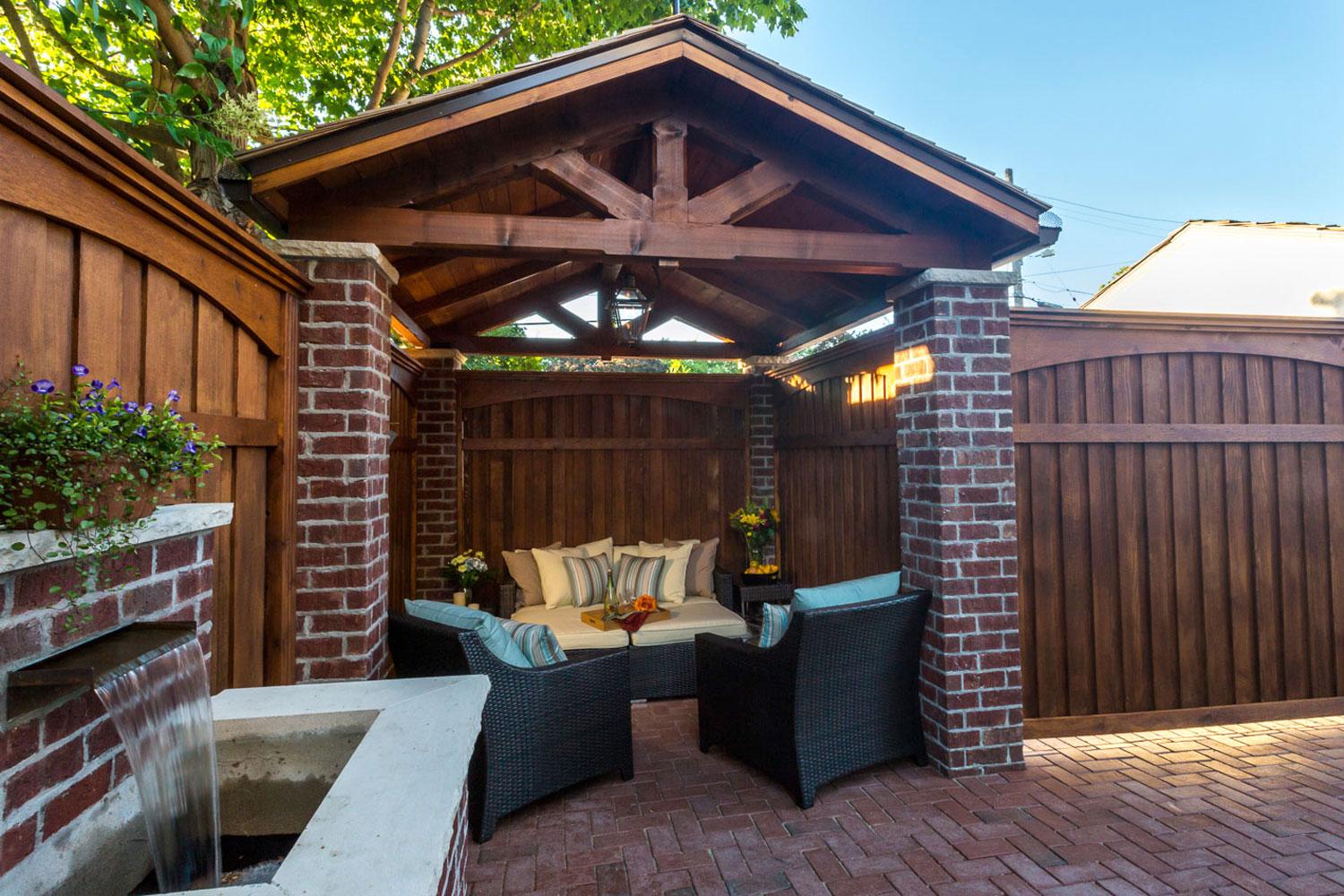 Cozy outdoor patio with seating under wooden pergola.