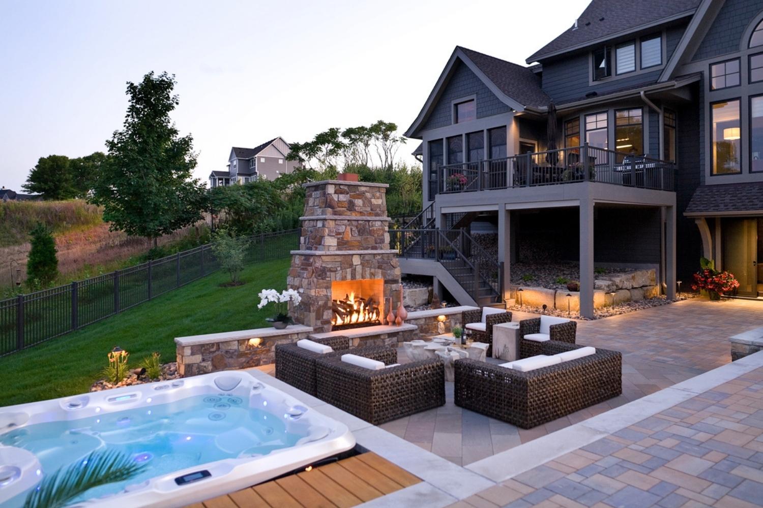 Luxury patio with fireplace and hot tub.
