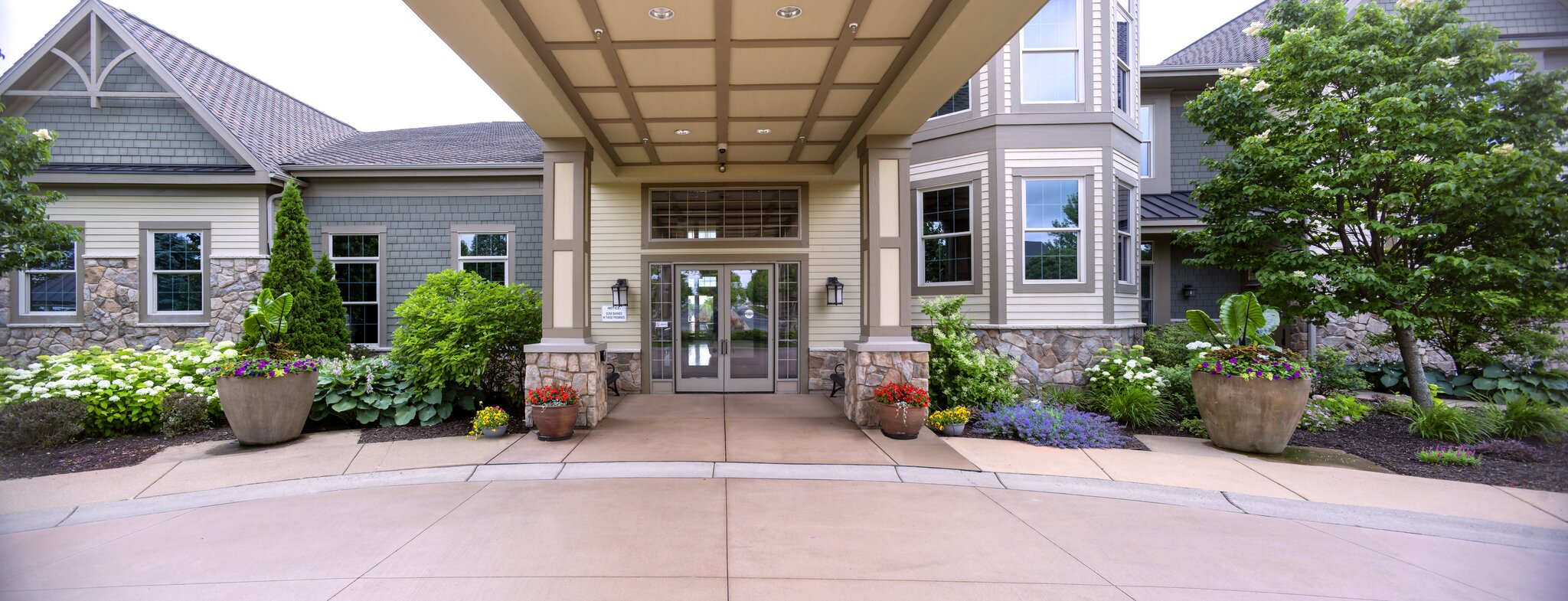 Charming building entrance with lush landscaping.