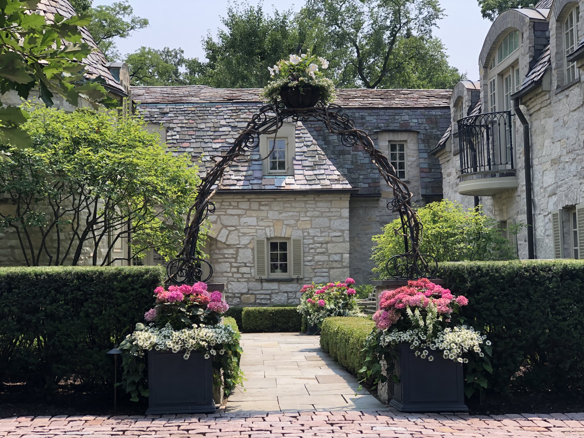 Charming stone house with garden archway and flowers.
