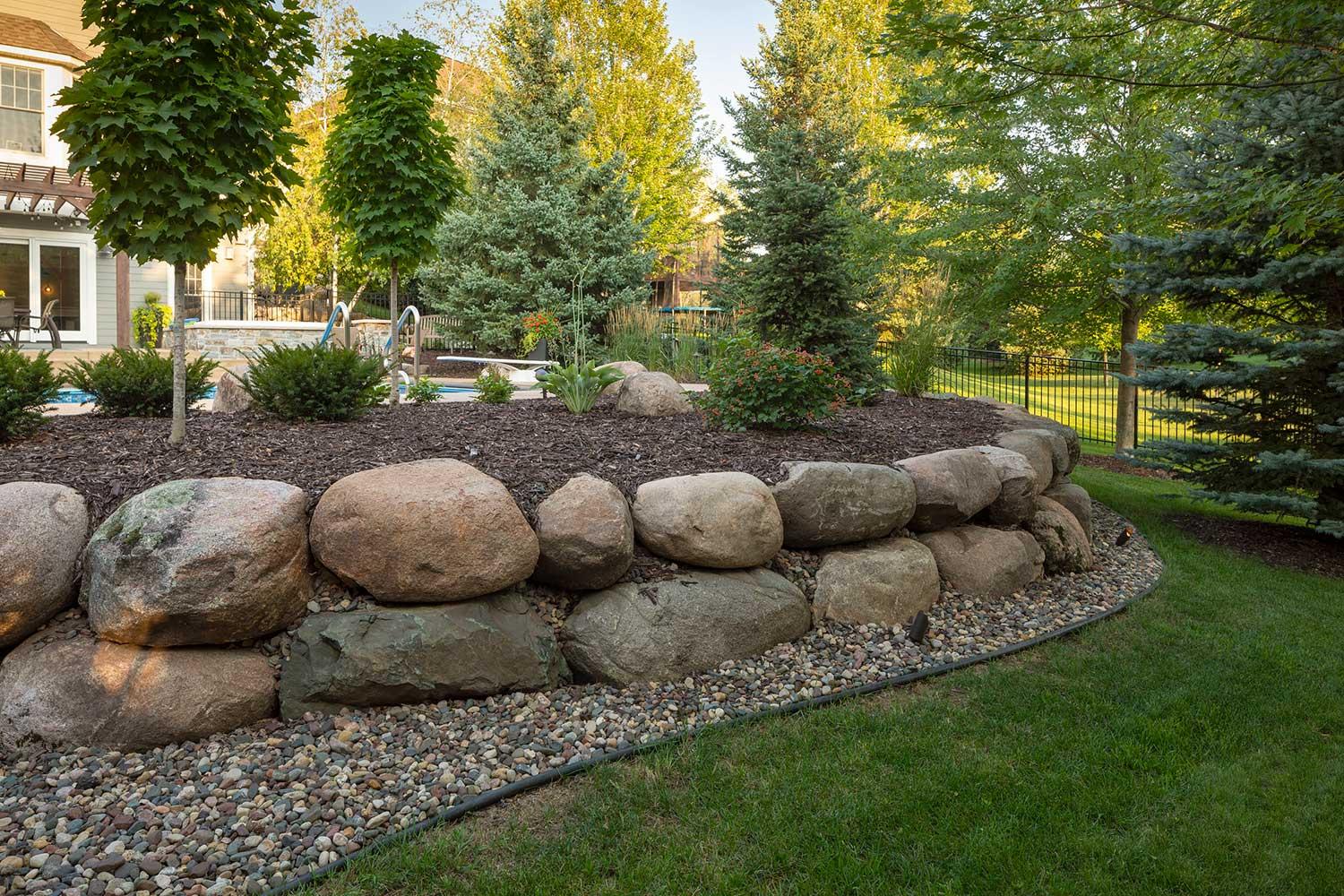 Beautiful backyard garden with trees and stone wall.