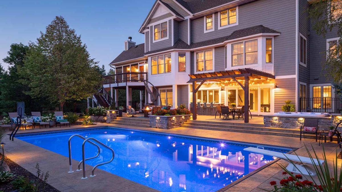 Luxury home with backyard pool at dusk.
