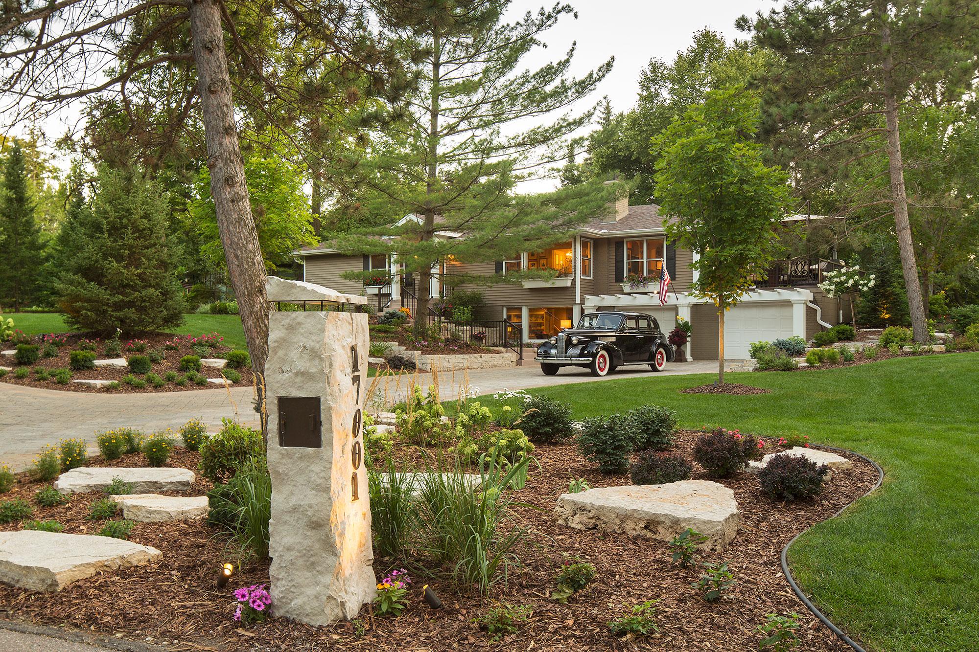 Lush landscaped lawn with vintage car and modern house.