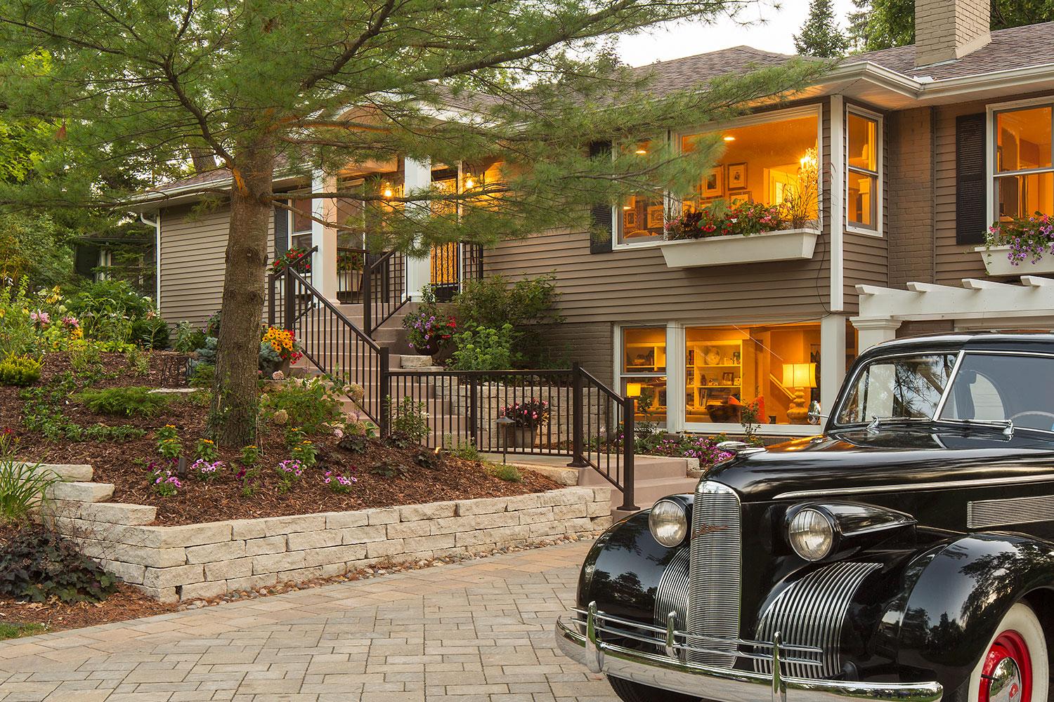 Classic car parked outside suburban house at dusk.