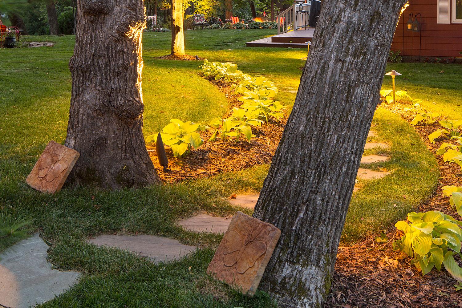 Garden path with yellow flowers and butterfly plaques.