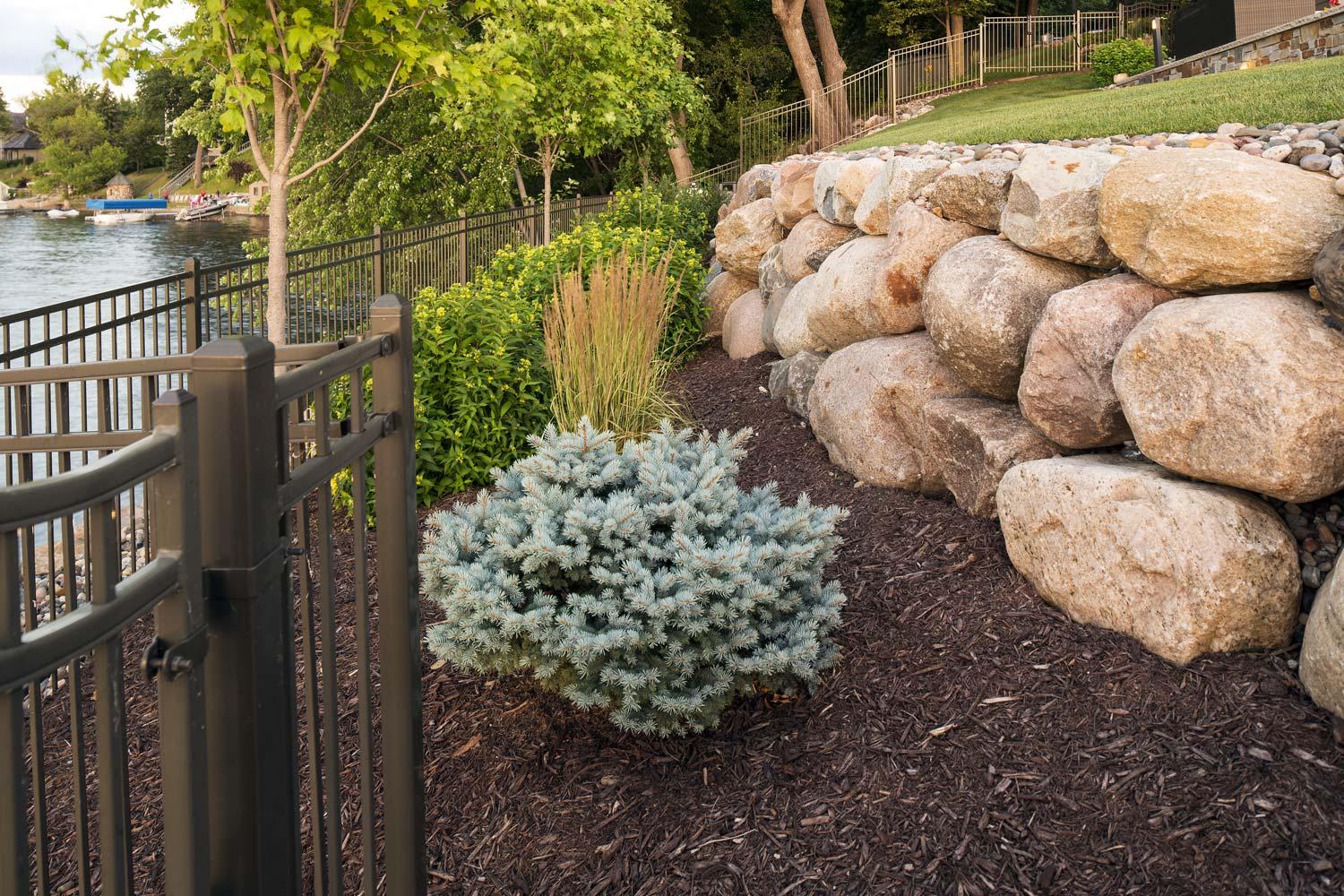 Landscaped garden by the lake with stone wall.