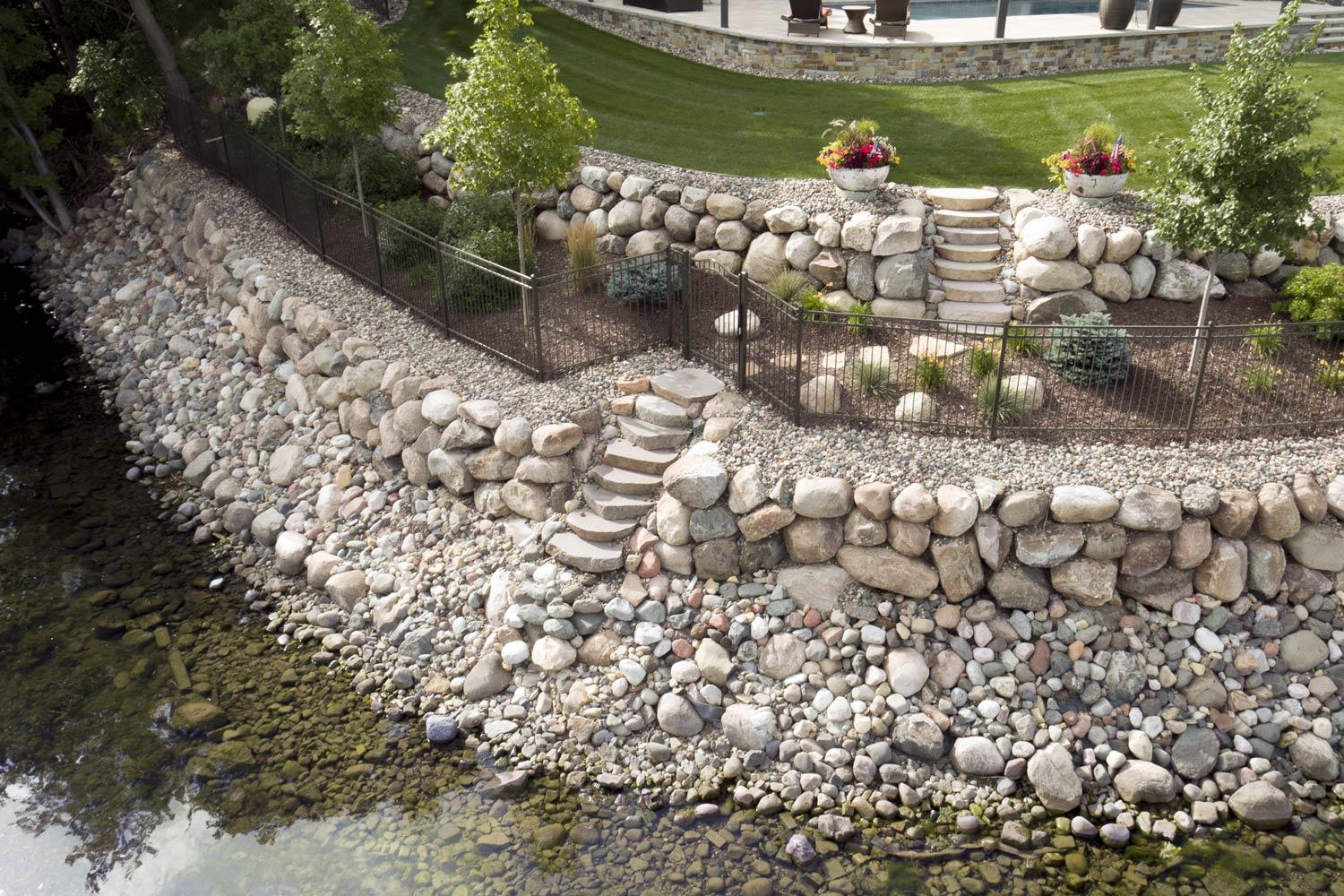 Stone retaining wall by water with garden steps.