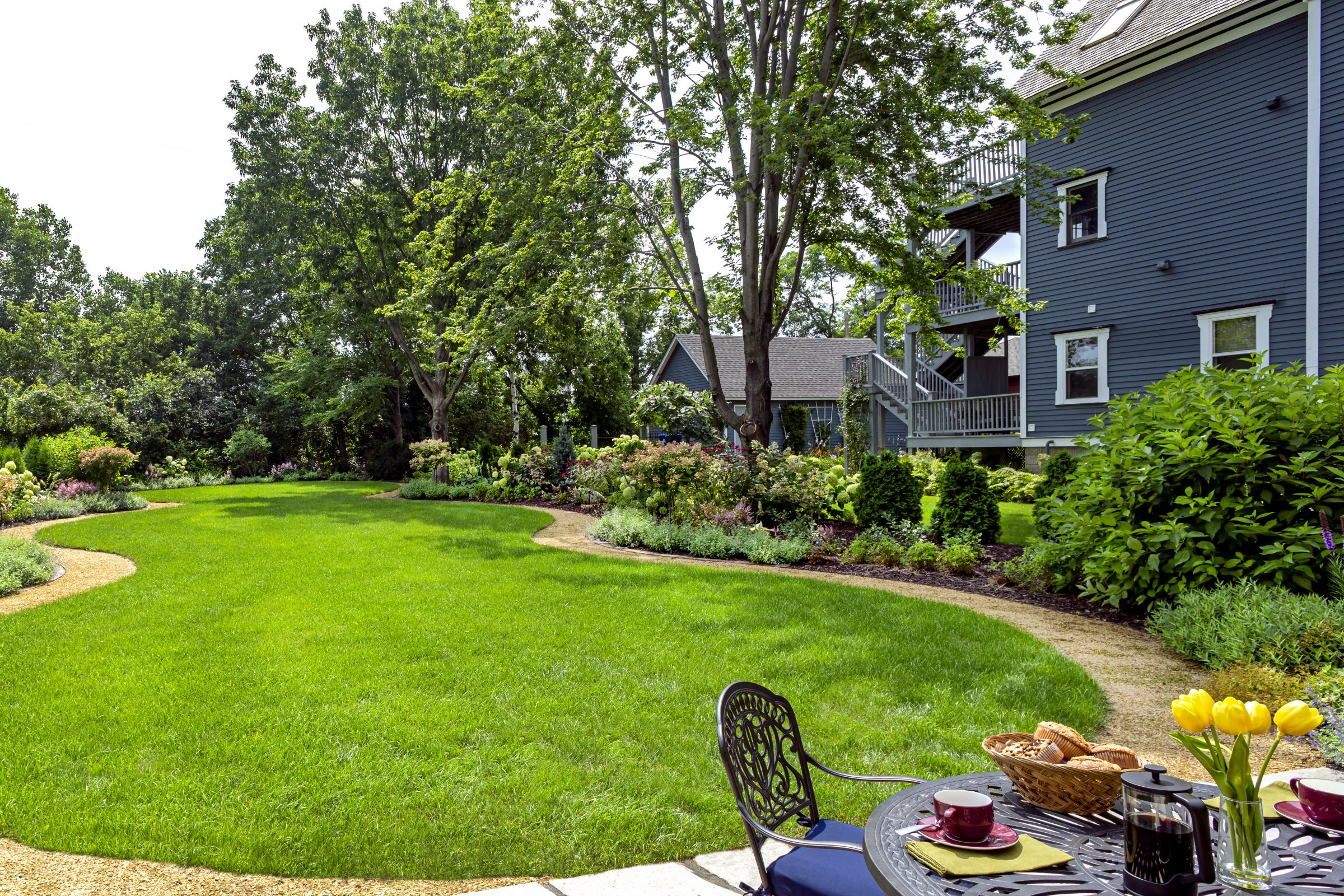 Green backyard garden with flowers and seating area.
