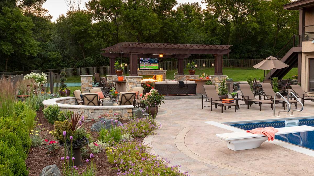 Outdoor patio with pool, seating, and TV under pergola.