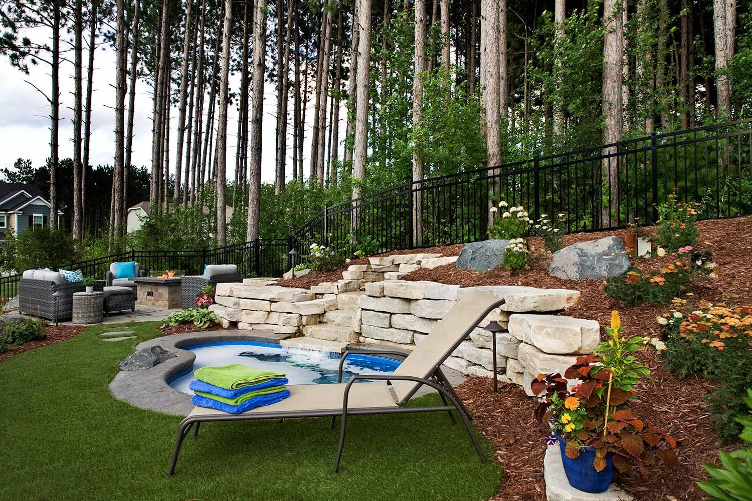 Backyard patio with jacuzzi and lounge chair.