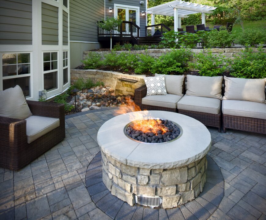 Modern patio with stone fire pit and seating.