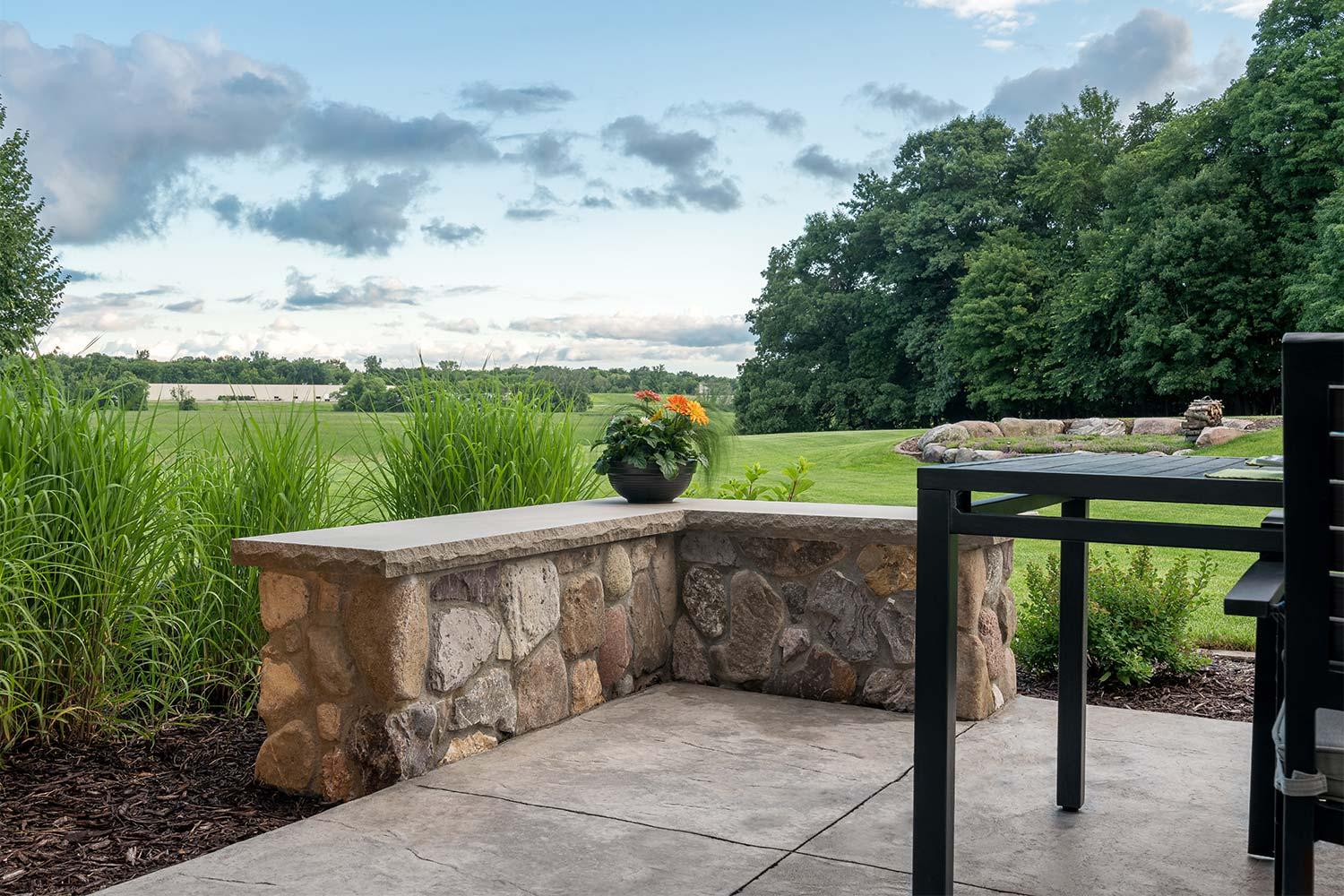 Stone patio with potted plant and scenic landscape.