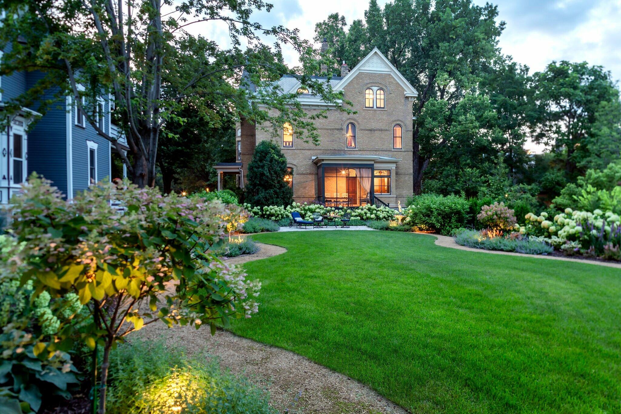 Beautiful backyard retreat with flowering hydrangeas, evening lighting, and inviting patio seating.