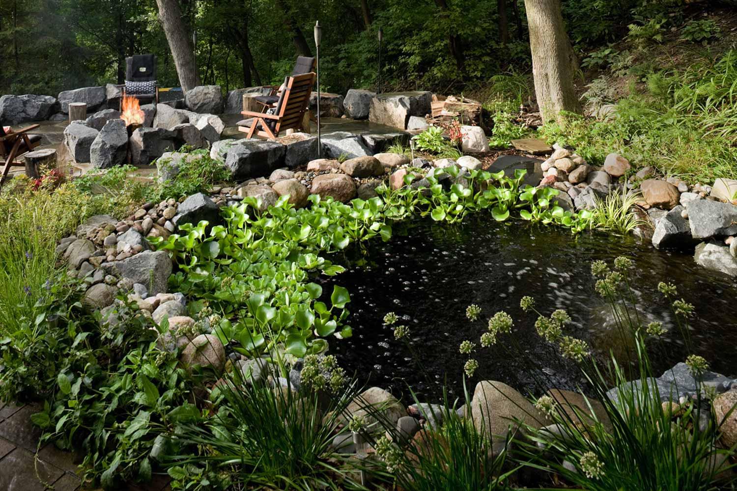 Backyard pond with seating and greenery.