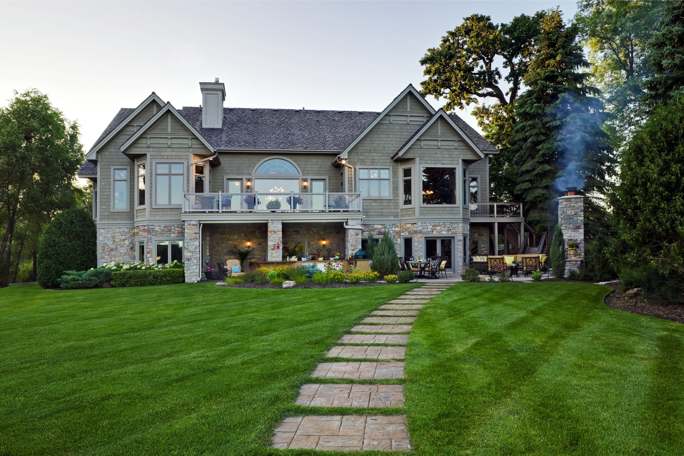Large house with a stone pathway and lush lawn.