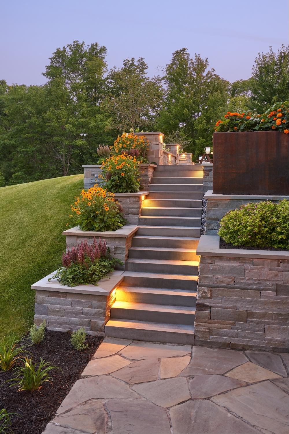 Garden steps with lights and flowers at dusk.