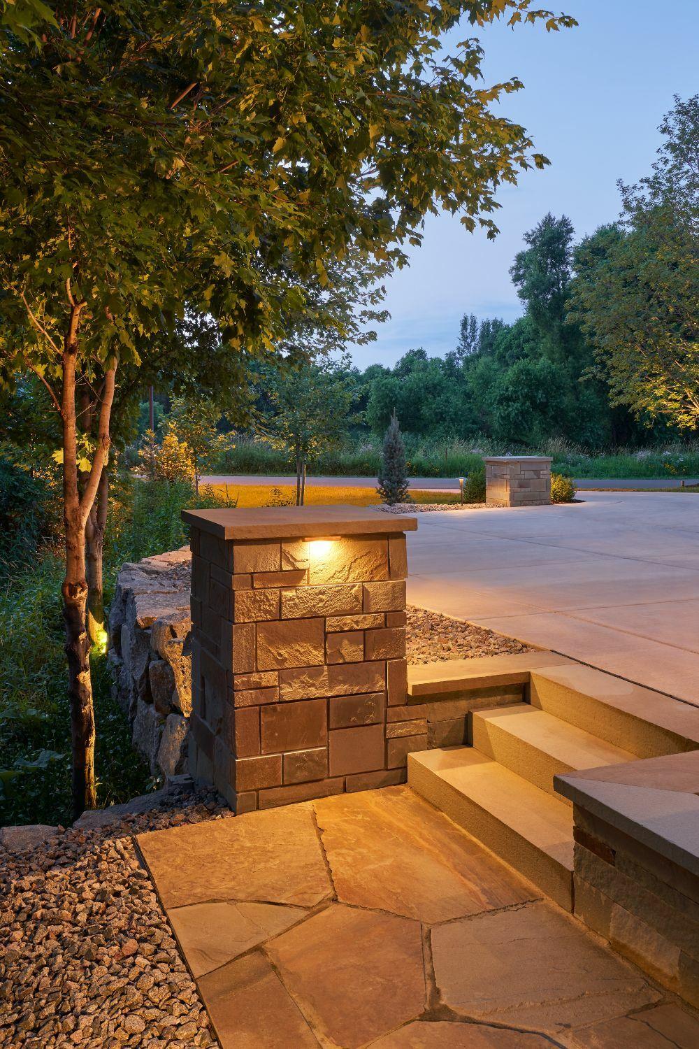 Illuminated stone patio with trees and steps.
