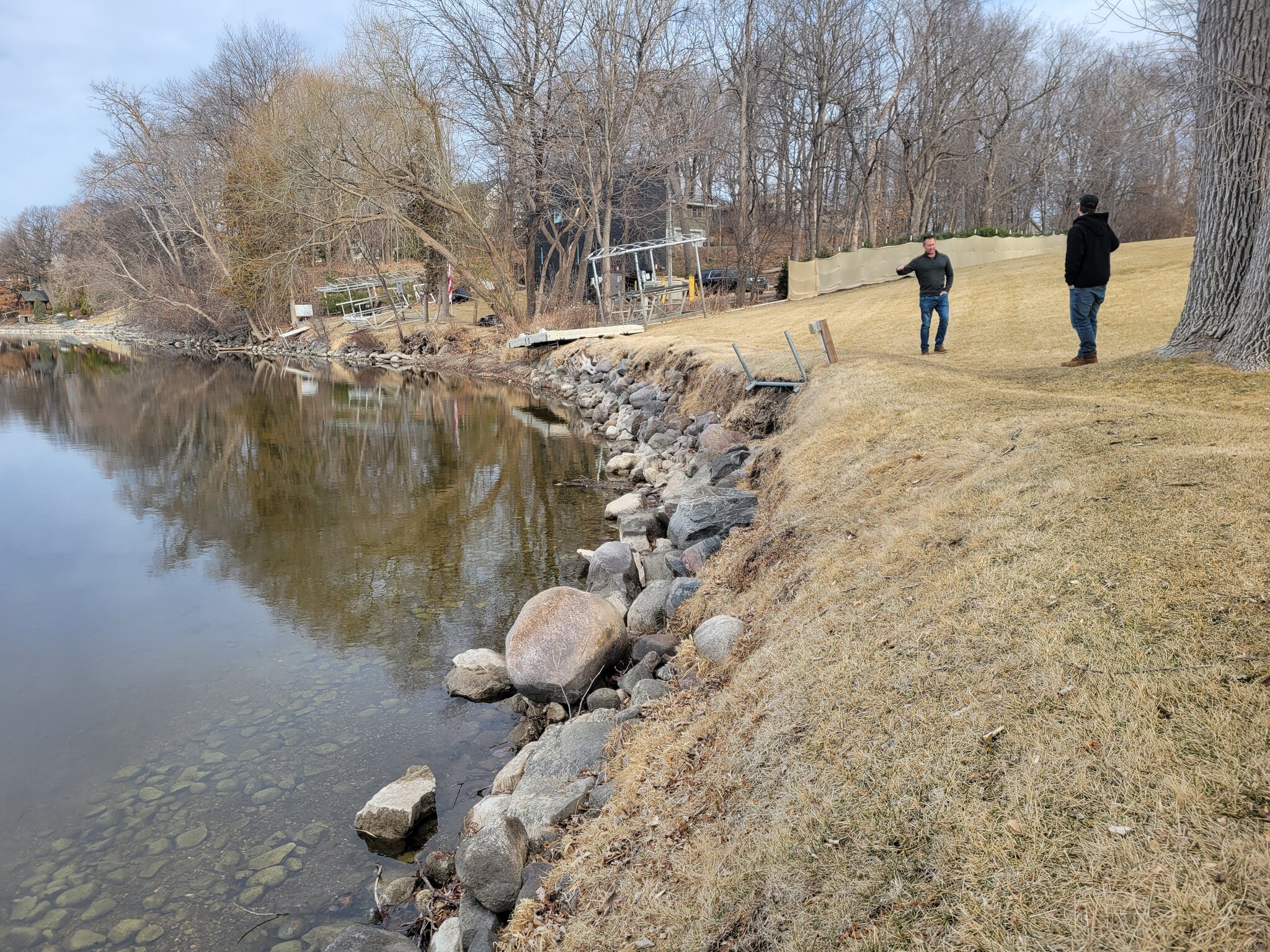 Two people walking near a pond in winter.