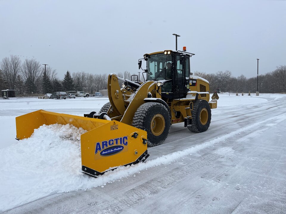 Snowplow clearing snowy parking lot