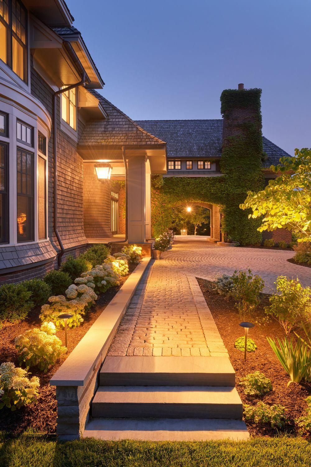 Illuminated pathway to elegant house entrance at dusk.