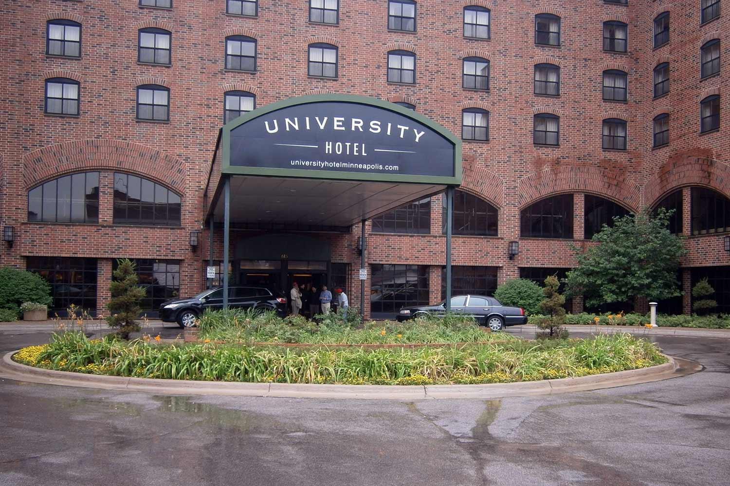Brick hotel entrance with cars in front.