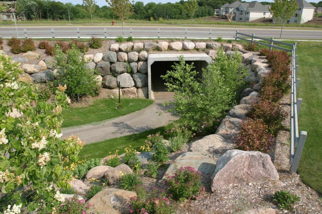 Pathway under bridge surrounded by stone walls.